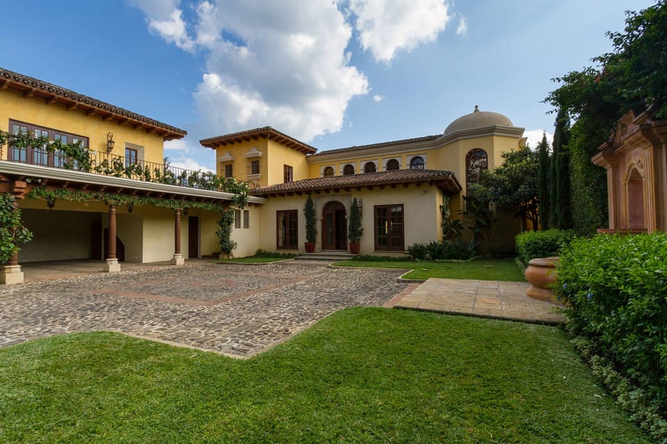 Open gates to front view of main house with fountain and separate garage and gym