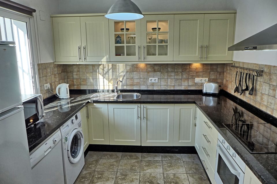 Modern kitchen with oven, hob, microwave, kettle, toaster, fridge, dishwasher