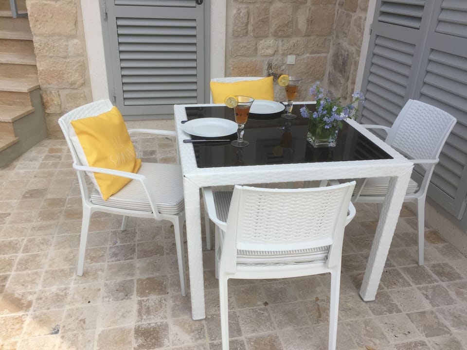 The dining table is at the far side of the L-shaped terrace, in the shade