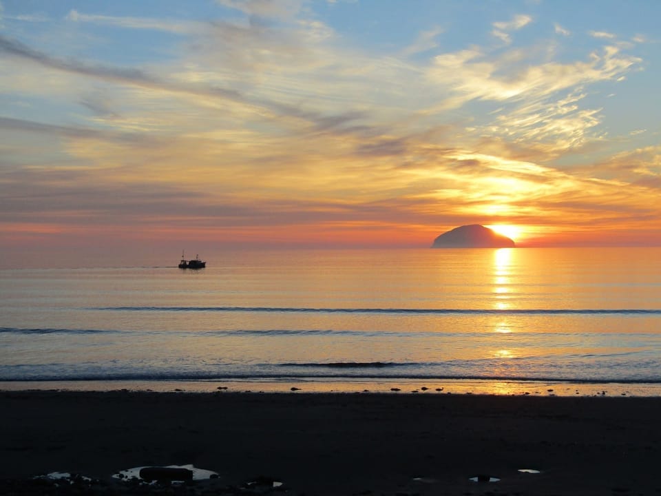 The beautiful town of Girvan with beach and sunset over on Ailsa Craig .