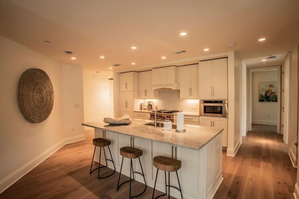 View into the kitchen from the living area. The large kitchen island has seating for 3 guests.  The hallway on the right leads to the King Guest Master and the King Guest Bedroom