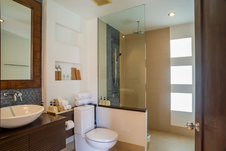 En-suite bathroom with single vanity, toilet, and indoor rainshower