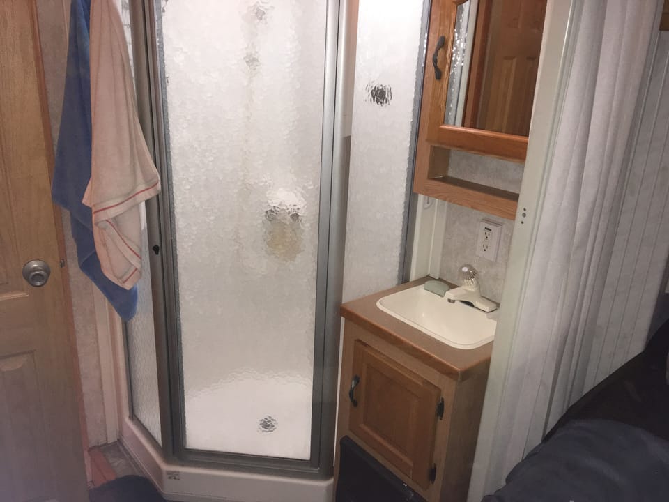 Shower and vanity with curtain and sliding door on each side of bathroom.