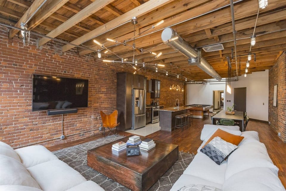- Cozy lounge with brick walls and mounted TV for movie nights   - Stainless kitchen and wood accents complete the industrial feel   - Ideal for guests wanting comfort with downtown convenience