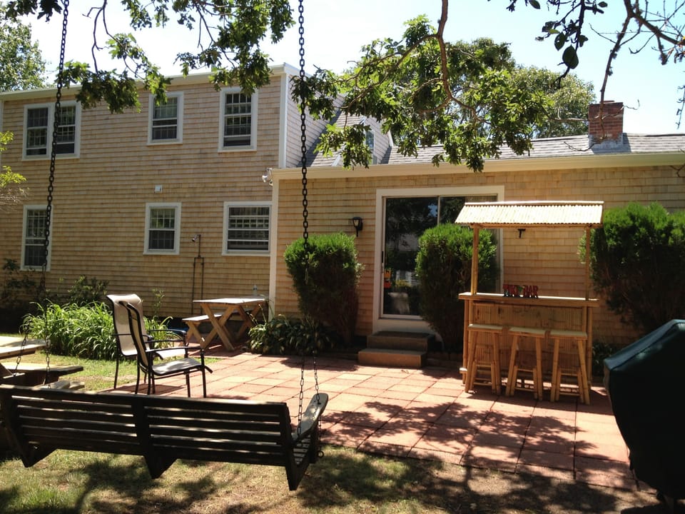Outdoor patio features TIKI bar, hammock swing chair, picnic table and gas grill