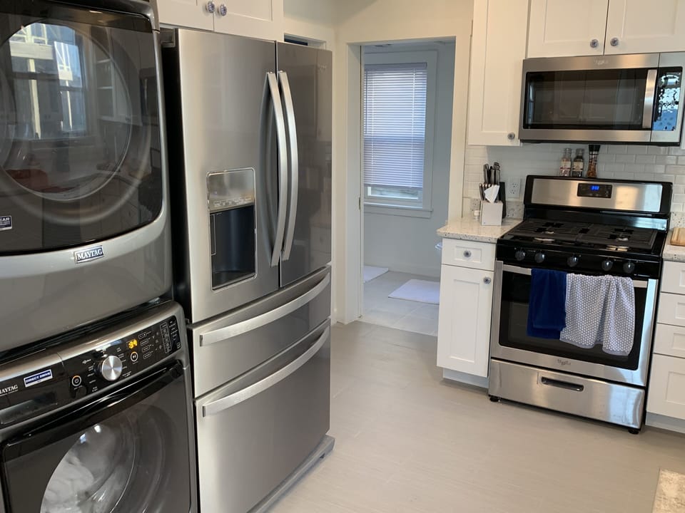 Kitchen with a view of the washer, dryer, fridge, gas stove and microwave