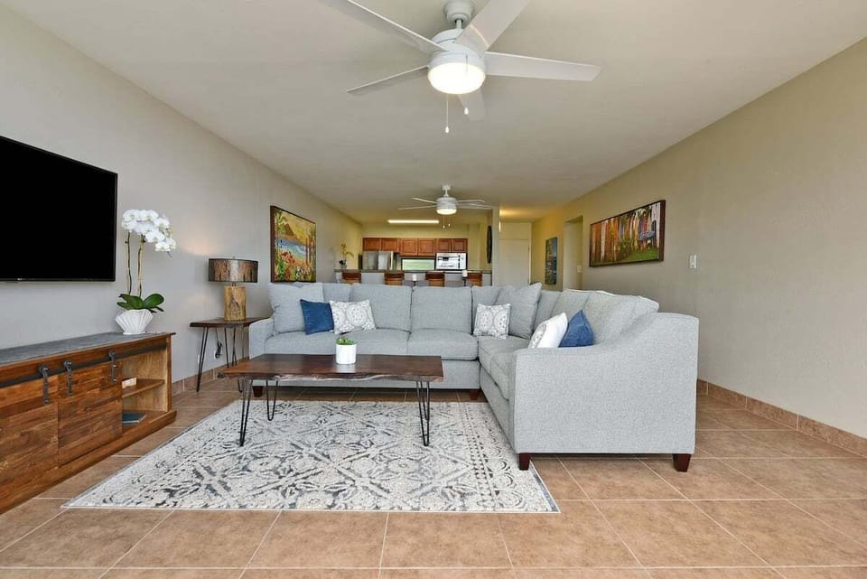 Living room with sectional sofa, coffee table, and tropical accents.