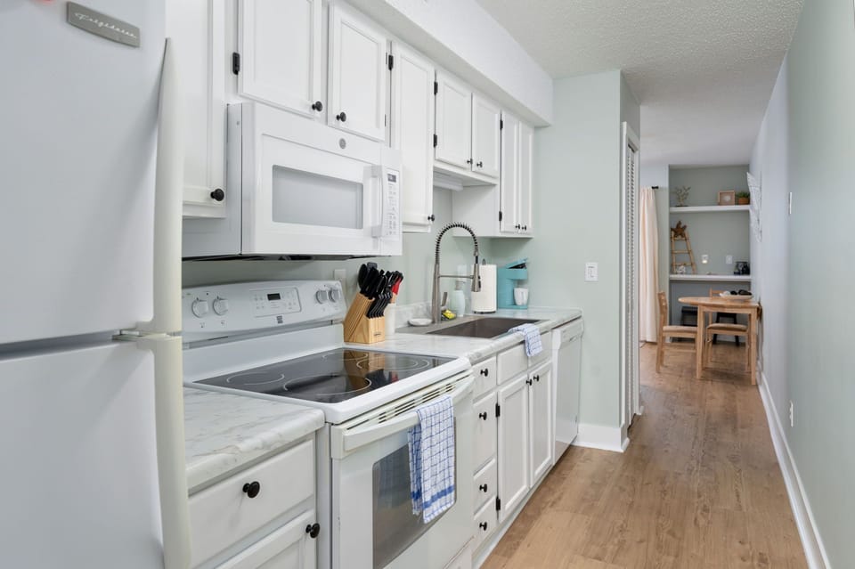 Bright galley-style kitchen with sleek white cabinetry, stainless-steel appliances, and modern finishes. Everything you need to prepare a great meal is at your fingertips.