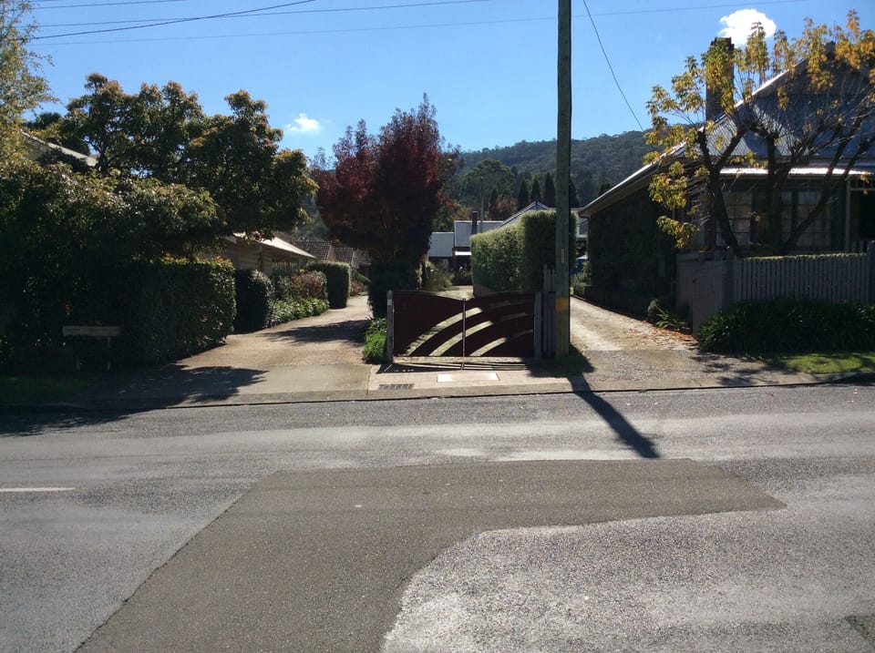 Bespoke rusty gate to the left of the telegraph pole is  the entrance