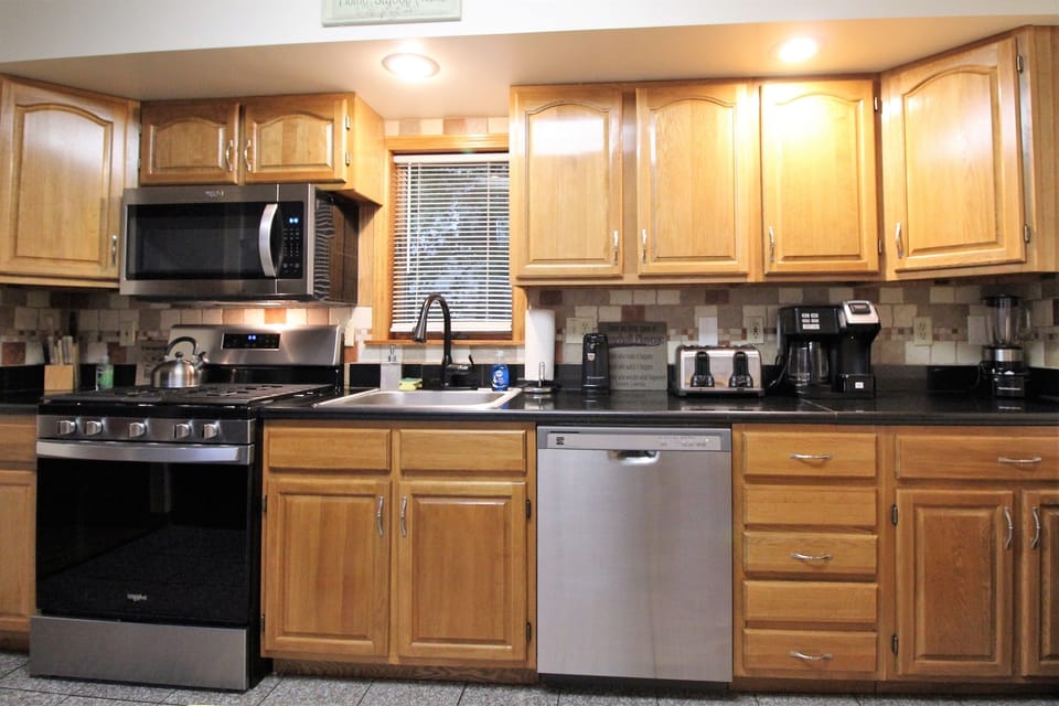 The fully appointed kitchen features granite countertops and flooring, new stainless steel appliances, and all the kitchen essentials
