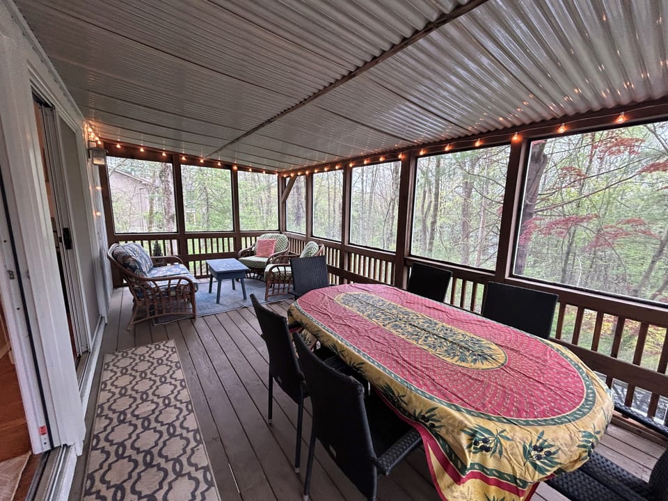 The screen porch has a large dining table and a soft seating area