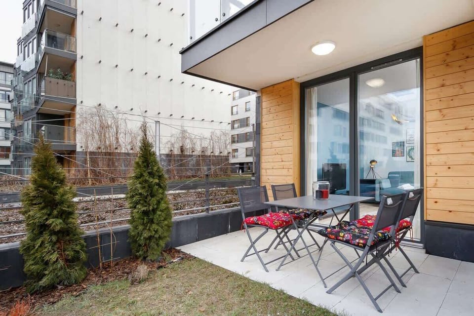 Outdoor seating on a patio with two chairs and a table, surrounded by a small garden, ideal for relaxation.