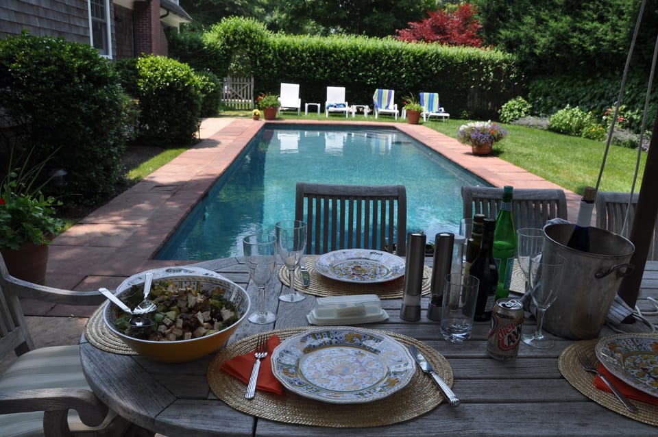 Outdoor patio and large, oval, umbrella covered table that easily seats 8.