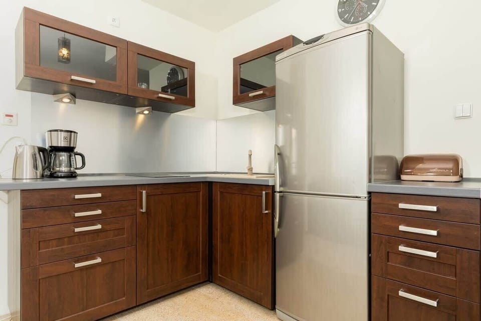 A compact kitchen with dark wood cabinetry, stainless steel appliances, and a small window, blending style with practicality.