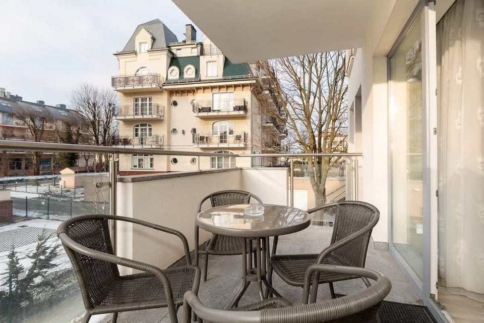 A balcony with a small table and chairs, providing a cozy outdoor space overlooking the surroundings, perfect for enjoying fresh air.
