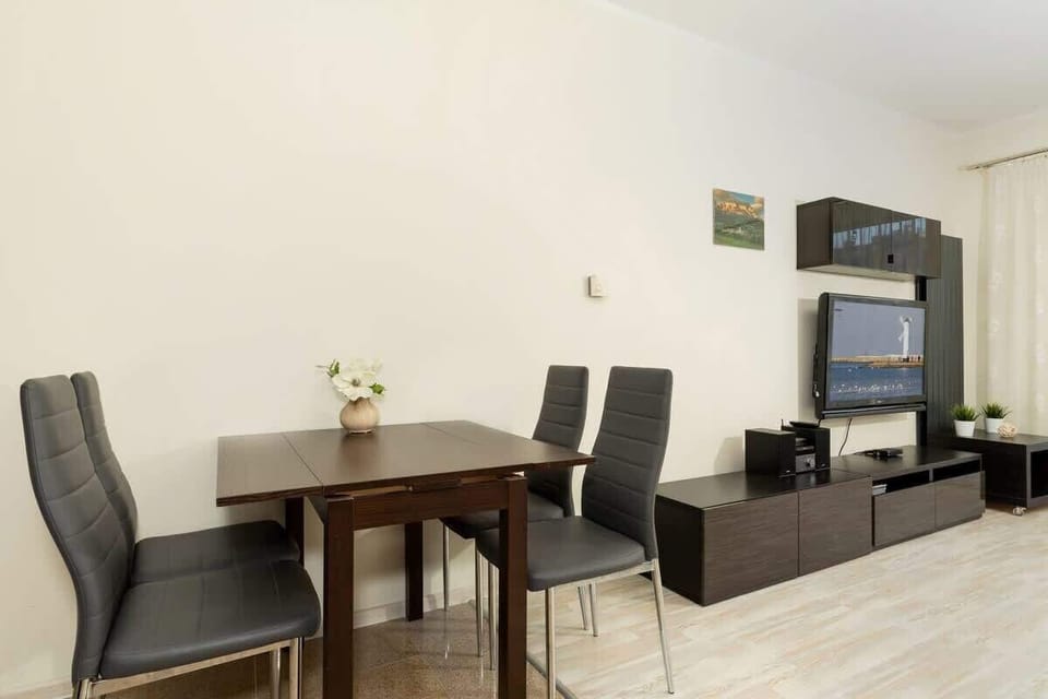 A dining area with a round table set for four, dark chairs, and a minimalist design, ideal for intimate meals or gatherings.