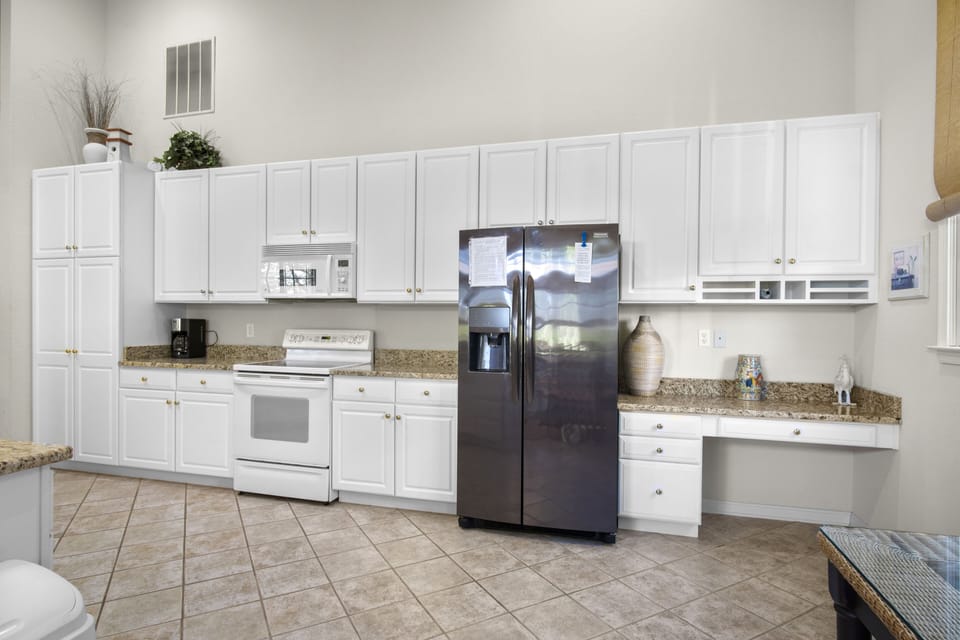 69 Willow Oak Ave - Gourmet Kitchen and Breakfast Bar - This bright, contemporary kitchen features an expansive wall of crisp white cabinetry and sleek granite countertops. A large black side-by-side refrigerator provides ample storage, while the open-concept design integrates a raised breakfast bar for casual dining.