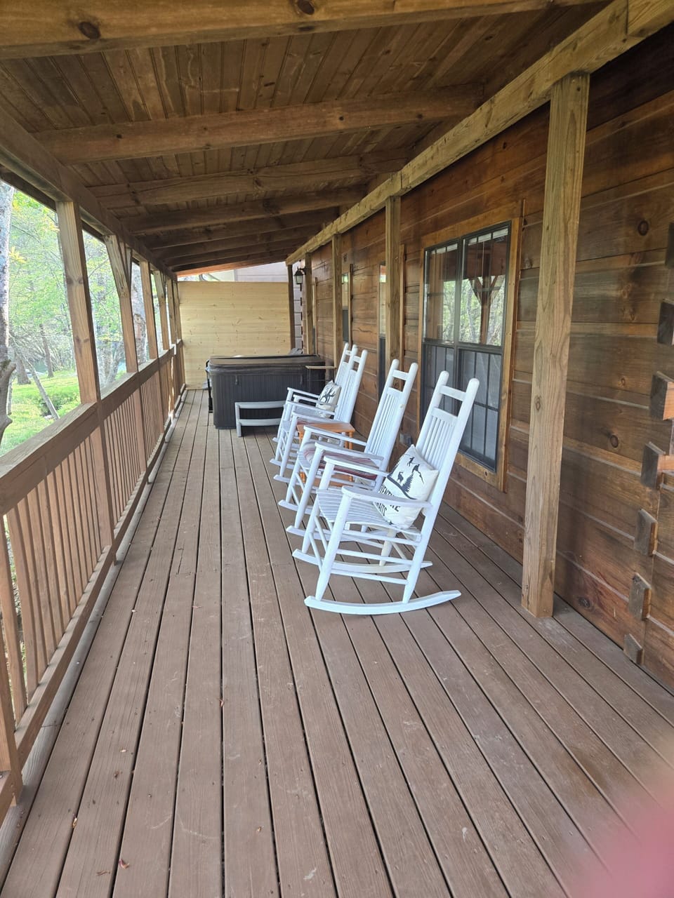 Large deck with four rocking chairs, hot tub and two chaise loungers