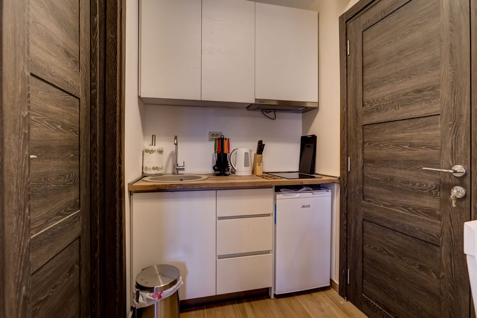 Private kitchen is equipped with dishes, teapot and fridge.
