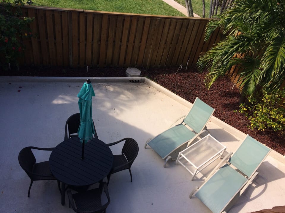 Large private patio with dining table, lounge chairs, grill, outdoor shower.