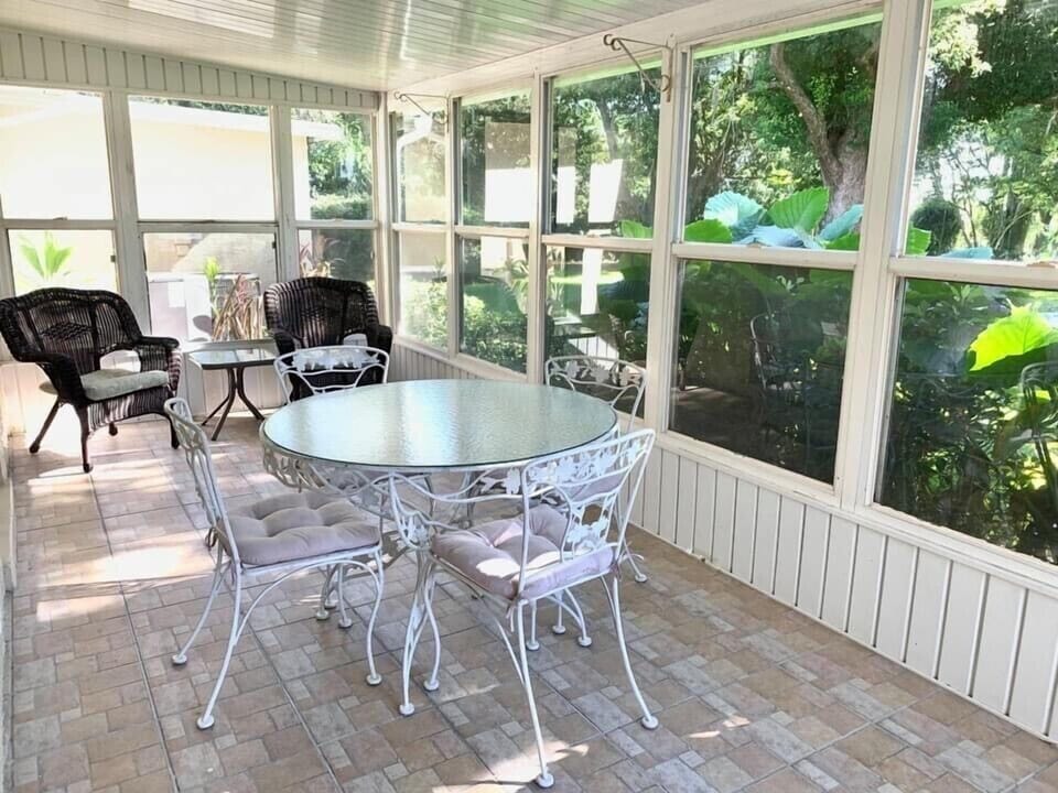 Rear lanai with table for four and two wicker chairs.