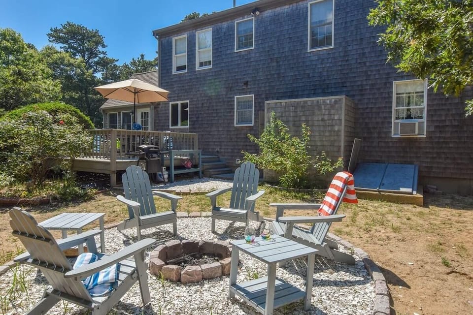 fire pit with 4 Adirondack chairs at rear of home