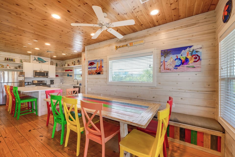 Gather around this vibrant dining table where colorful chairs invite laughter and memories over every meal in this cheerful space.