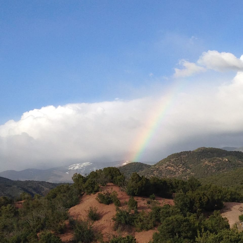 Beautiful rainbow above hiking trails with mountains in background.