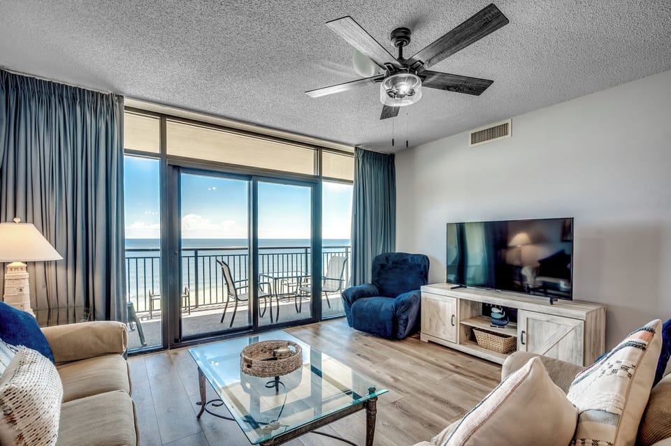 Living room with balcony access and large flat-screen TV