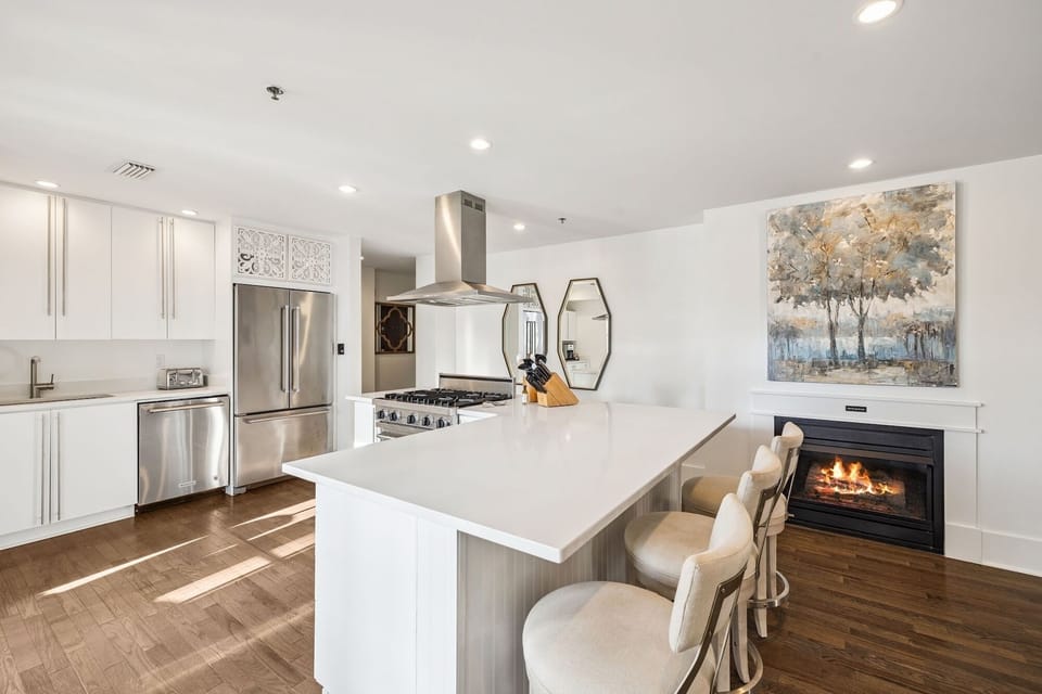 Your modern kitchen awaits with pristine white cabinetry, sleek appliances, and a cozy fireplace for relaxed evenings.