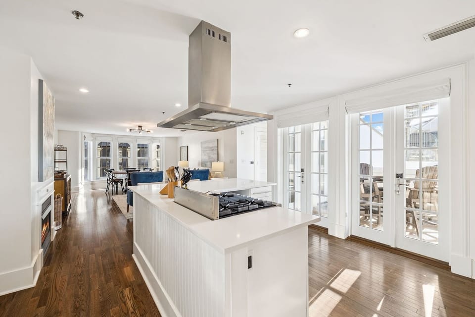 Cook in your bright open kitchen with sleek white island, stainless steel range hood, and warm wood floors flowing into elegant living spaces.