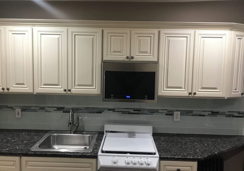 kitchen granite countertop with glass backsplash & over the range microwave hood