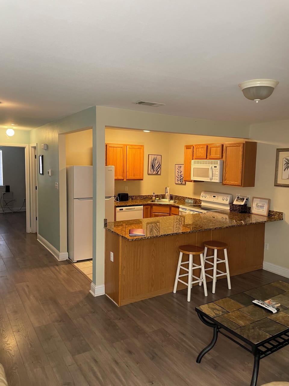 View from living room showing kitchen, bar stools and hallway.