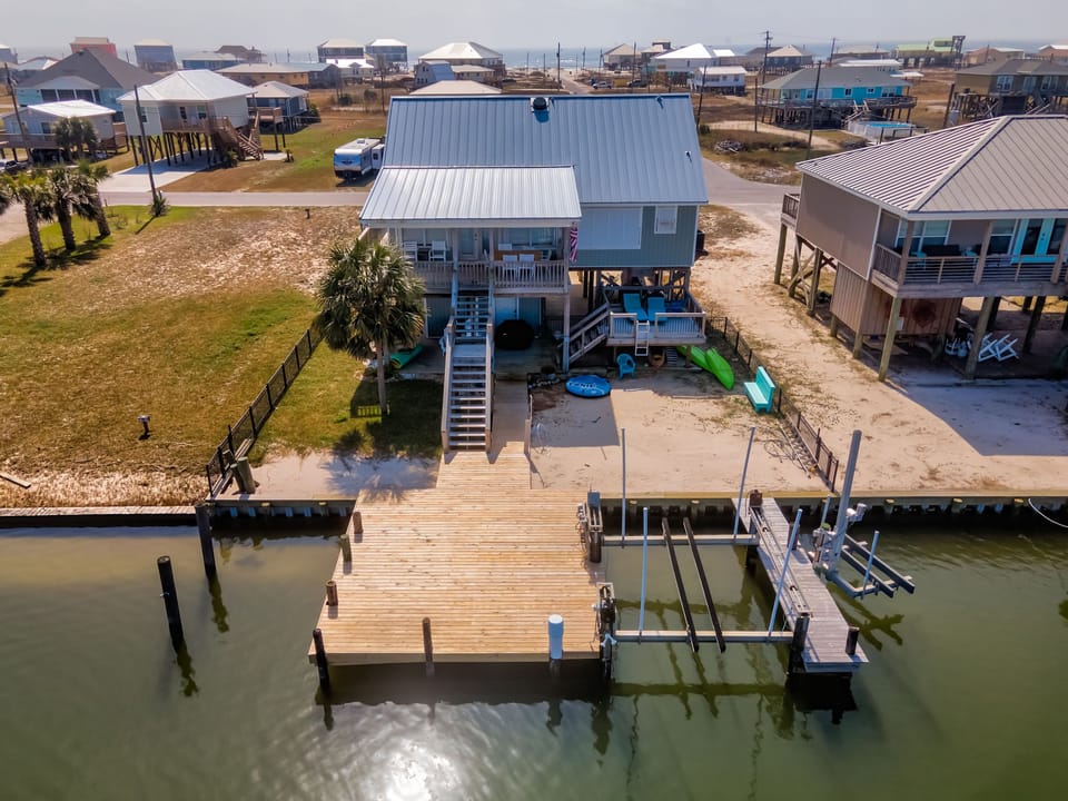 Waterfront beach house with private dock, kayaks, and boat lift positioned on scenic canal in coastal community.