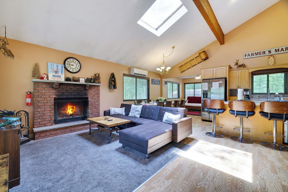 Rustic open-plan living: sectional, 55" TV, fireplace, minisplit for coziness.