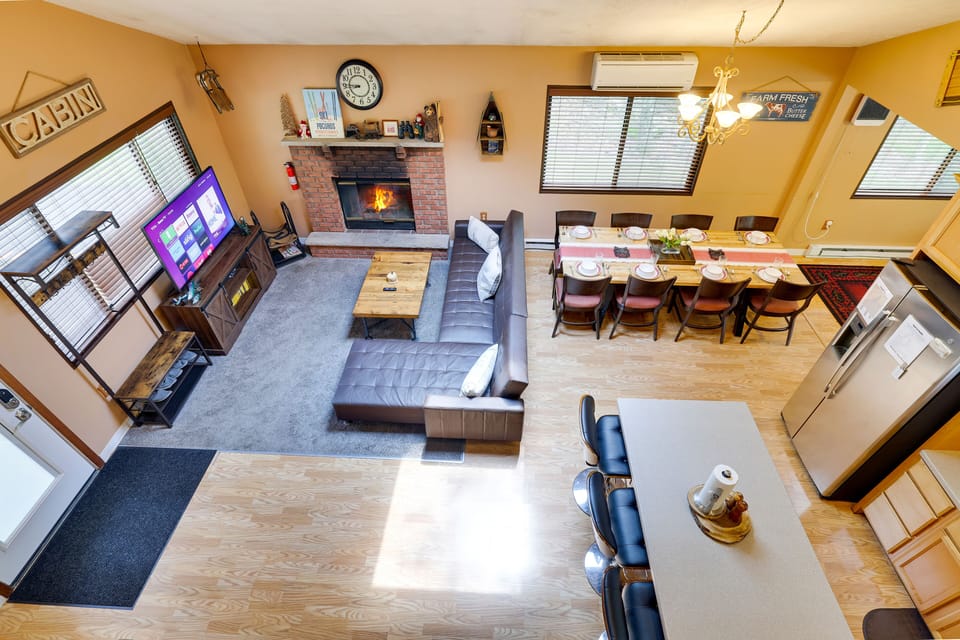 Rustic open-plan living: sectional, 55" TV, fireplace, minisplit for coziness.
