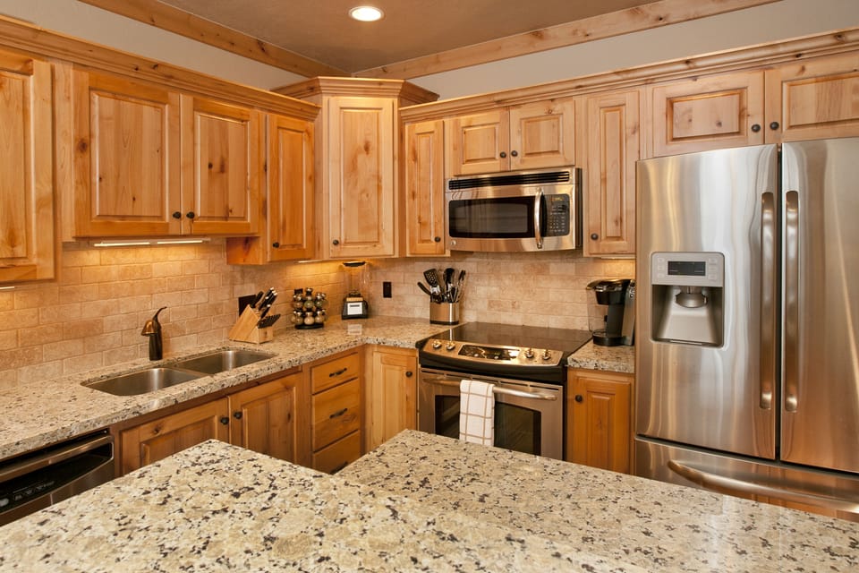 Step into your fully-equipped gourmet kitchen where warm wood cabinets and granite countertops create the perfect space for preparing memorable meals during your stay.