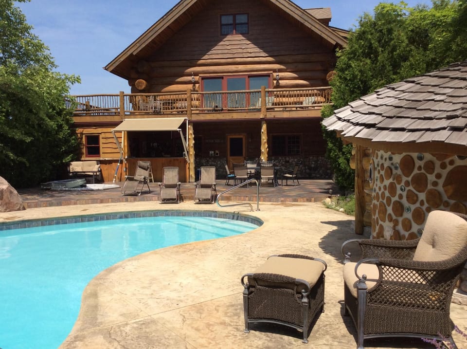 Pool and sauna foreground. House with outside bar background 