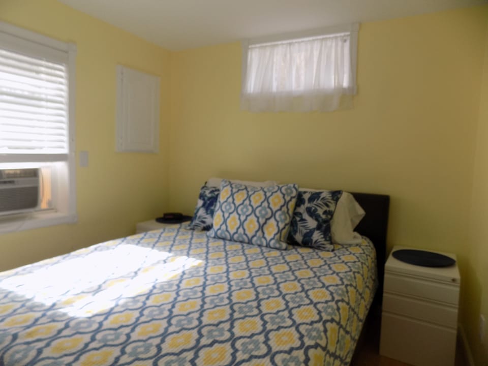 Bedroom with comfy queen bed and air conditioner.