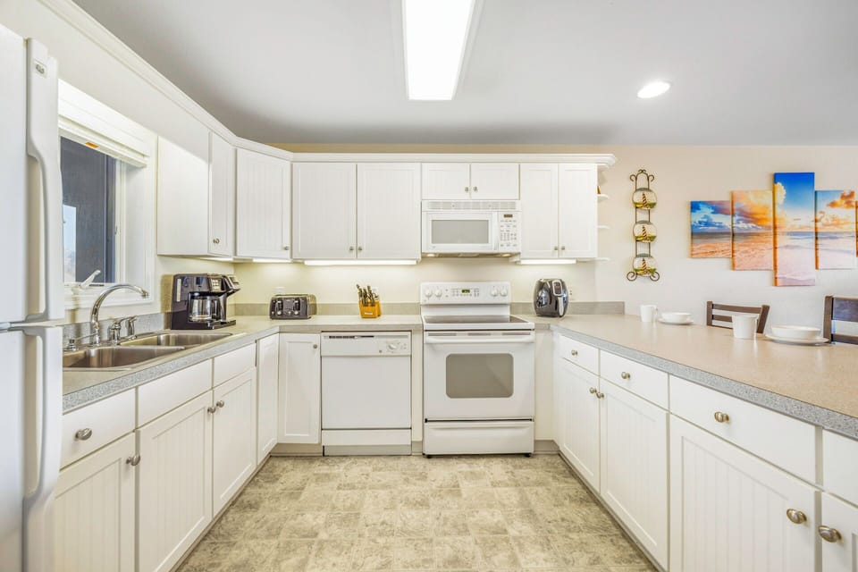 Your spacious kitchen invites culinary adventures with pristine white cabinets, modern appliances, and ample counter space for cooking memorable meals together.