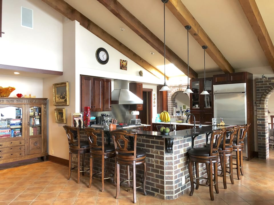 High chairs around high countertop with kitchen built inside.