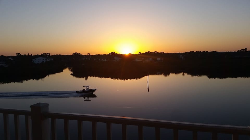 A boat breaks the glass-like surface of the intracoastal at sunrise