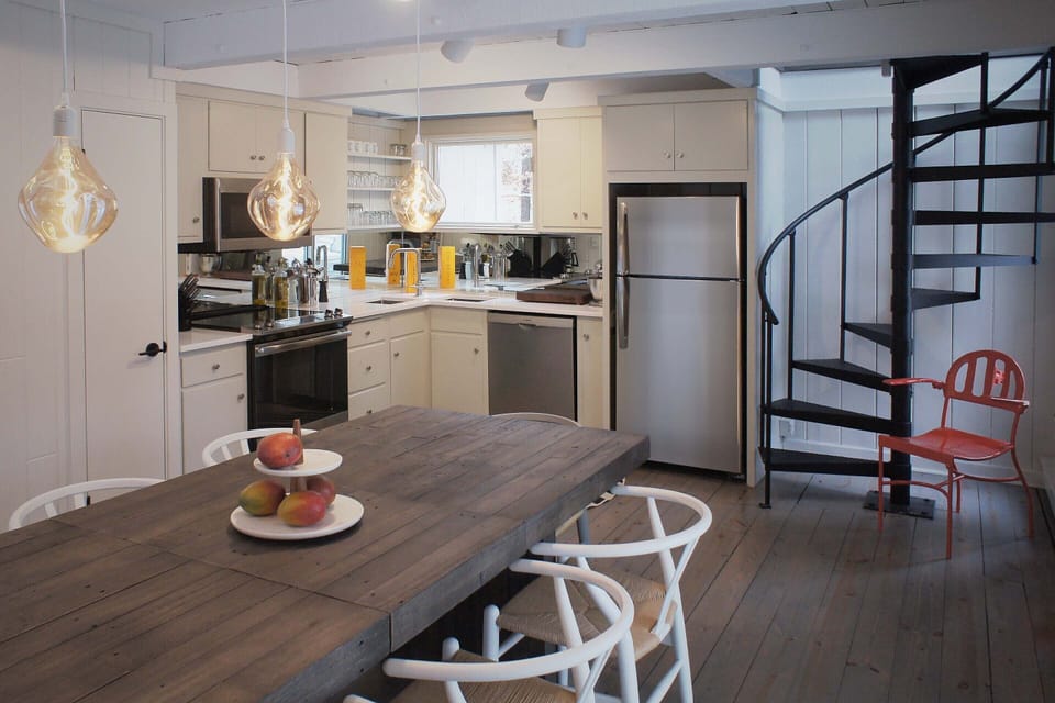 Remodeled kitchen opens to dining with vintage spiral stair to media room above.