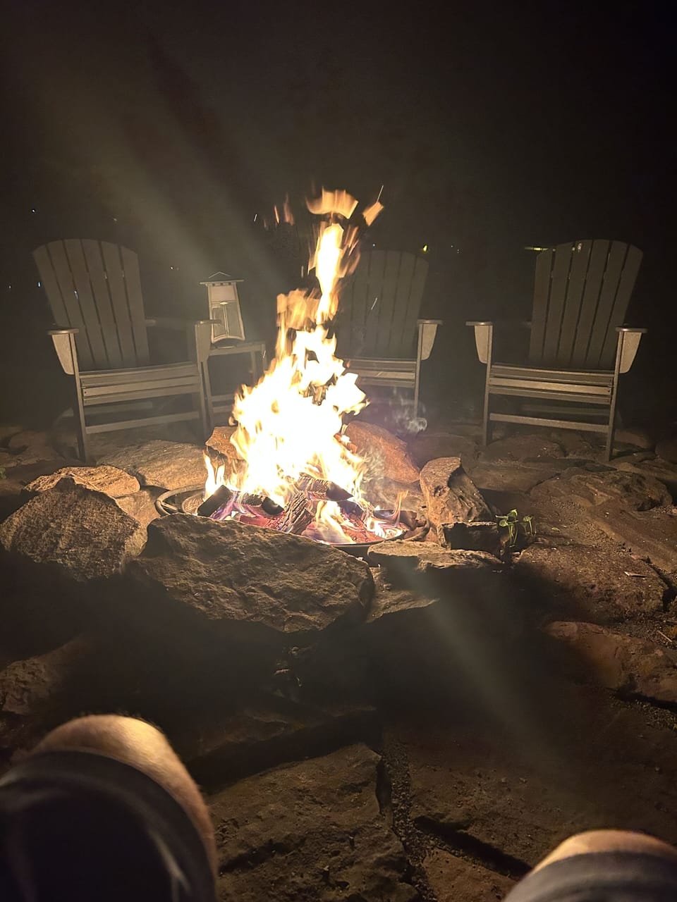 Huge stone fire pit with Adirondack chairs all around