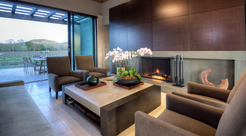 beautiful living room with a fire place opens to vineyard and outdoor dinning 