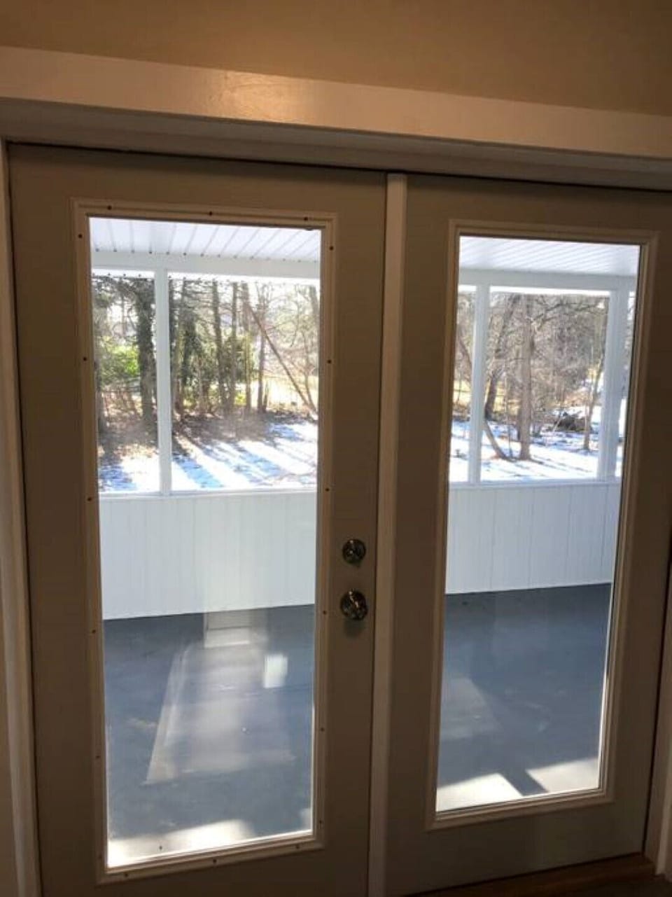 View out double glass doors in kitchen to screened in porch and backyard.