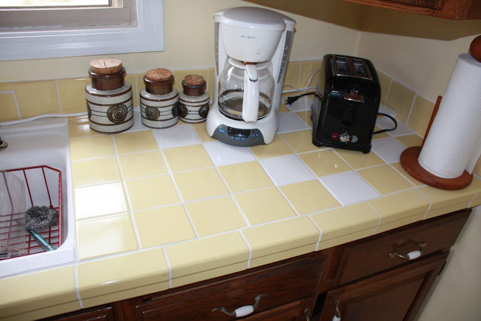 kitchen counter w/ coffee maker, toaster and ceramic jars.