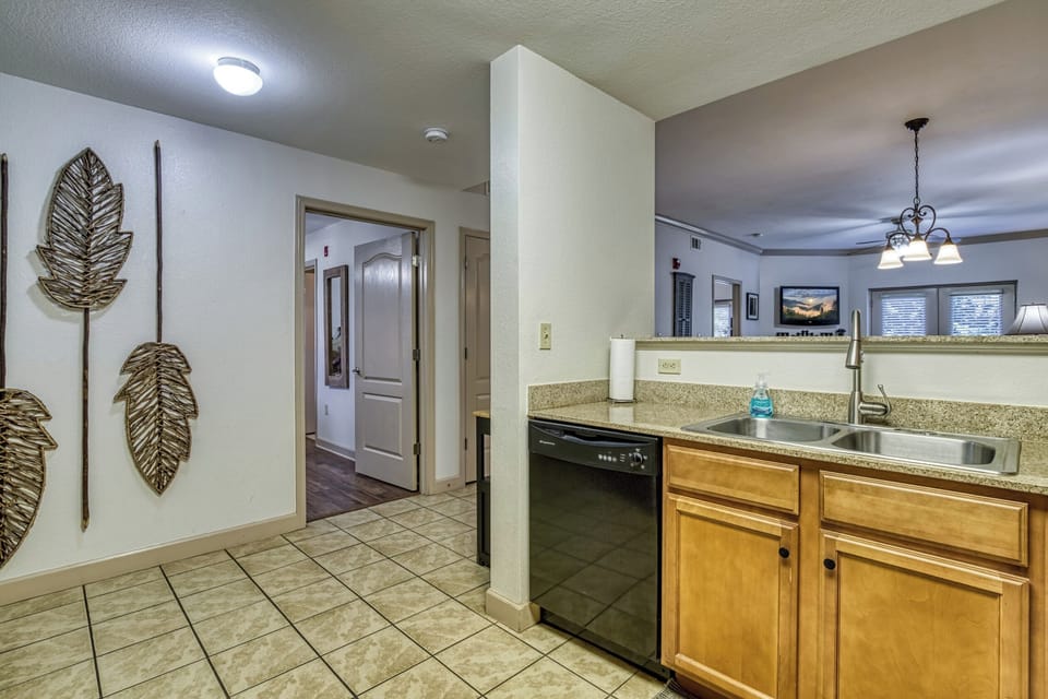 Art, Granite Countertop, Stainless Sink, Tile Floor, TV, Doorway, Dish Washer.