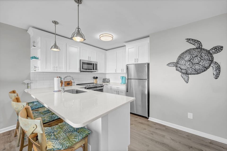 Prepare your favorite meals in this bright, fully-equipped kitchen with modern appliances, ample counter space, and charming coastal décor that welcomes you home.