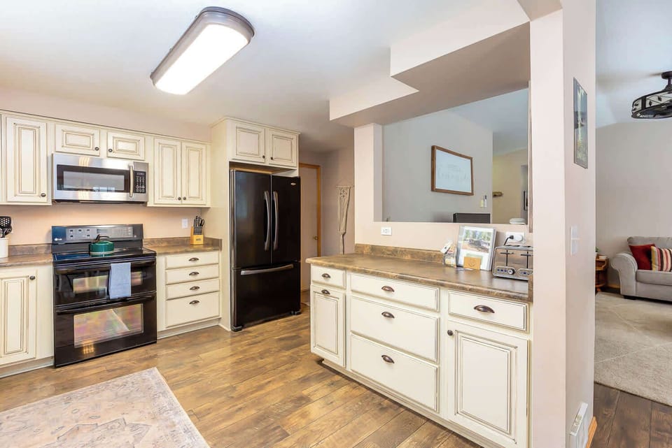 The kitchen is fully stocked with kitchen utensils and has a hidden garbage can. 